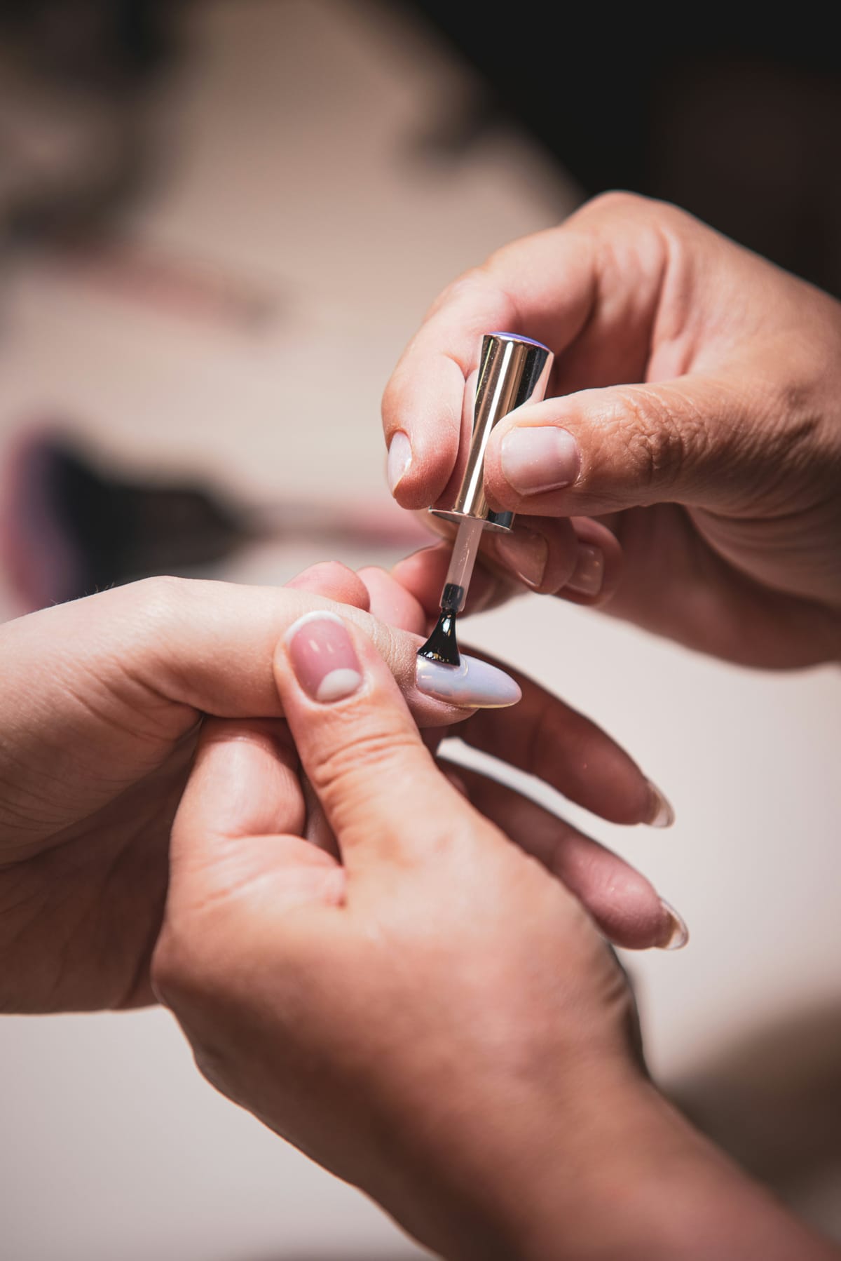 Handen van de nagelstyliste die een nagel lakt