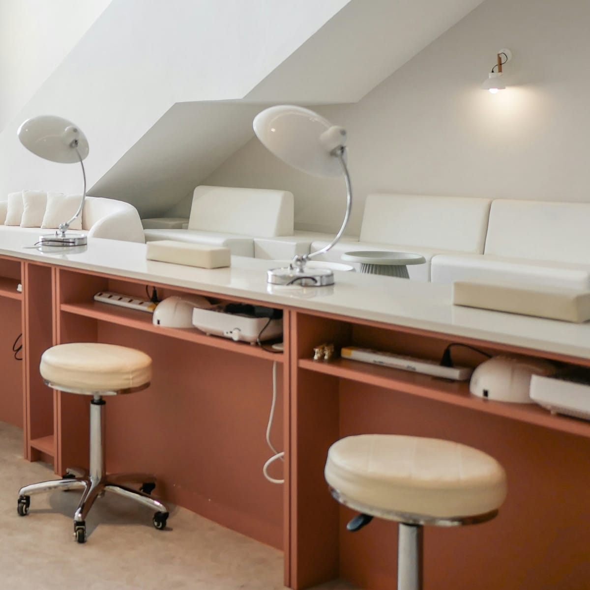 Manicuretafels met bureaulampen en krukken onder een schuin dak