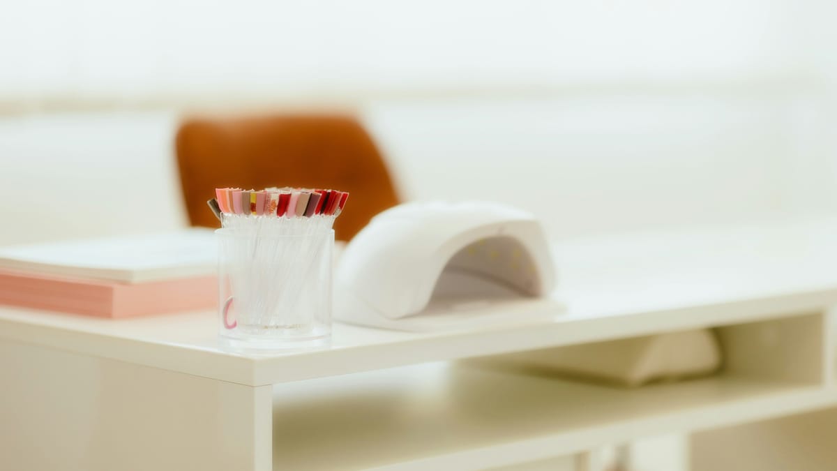 Witte manicuretafel met een nagellamp en een potje kleurstalen