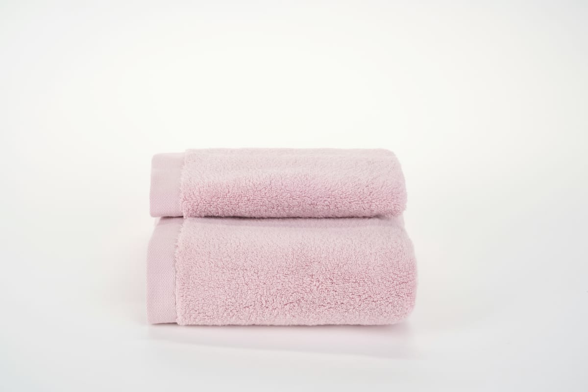 Twee opgevouwen roze handdoeken op een witte ondergrond