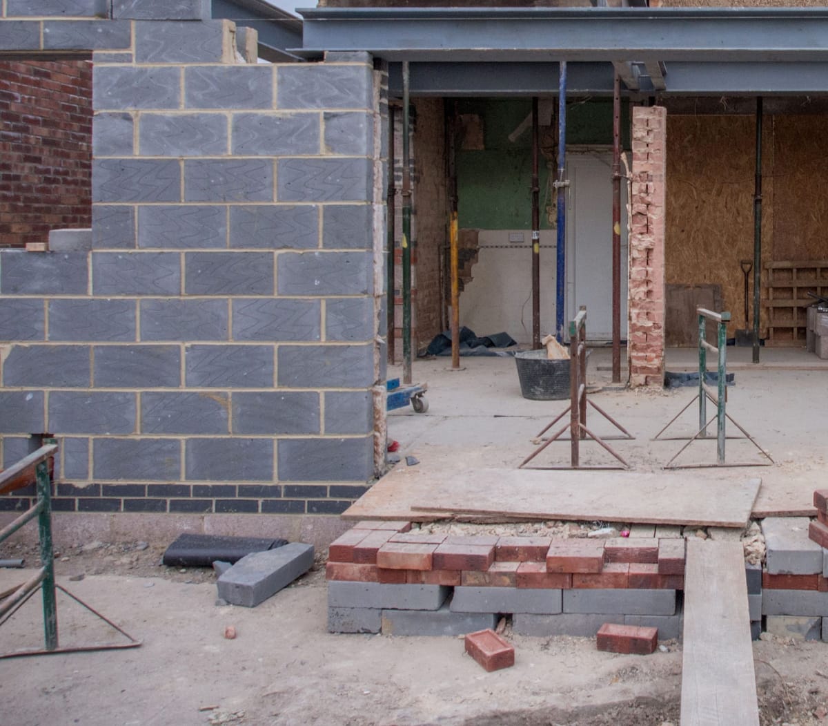 Extension under way: grey sand-lime brick walls, a steel beam and props at the back of a house
