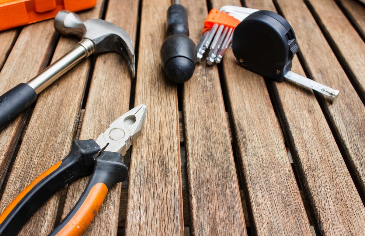 Hamer, tang en rolmaat op een houten werkblad