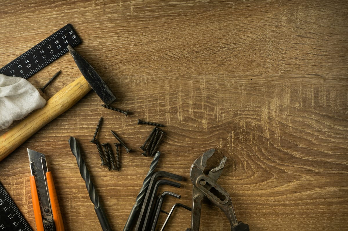 Hamer, winkelhaak, waterpomptang, inbussleutels en schroeven op hout