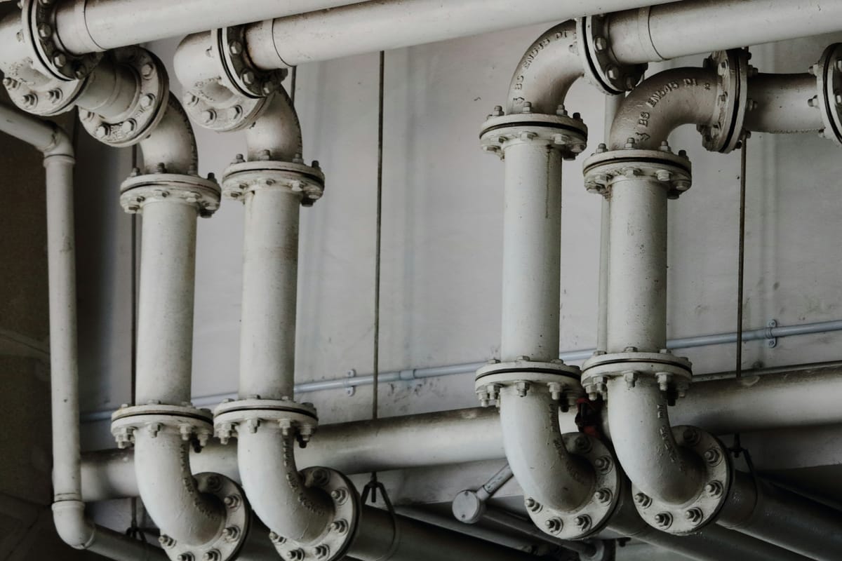 Wit geschilderde leidingen met flenzen in een technische ruimte