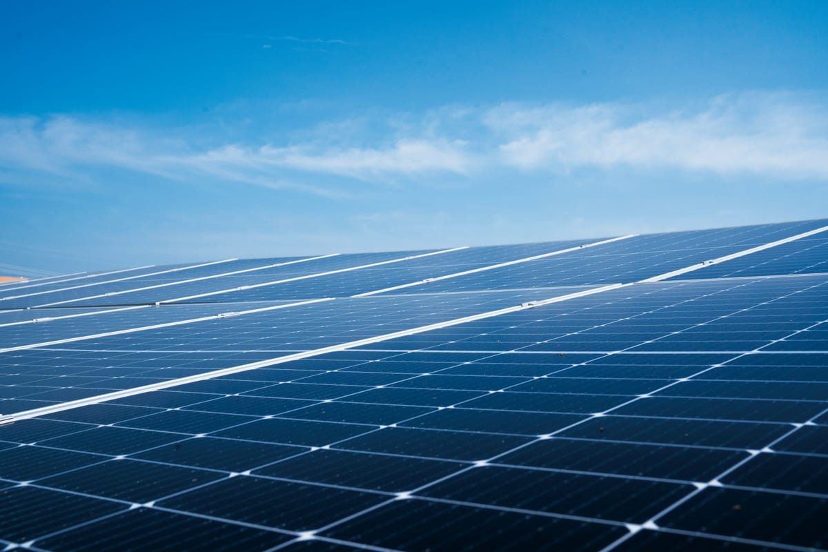 Rijen zonnepanelen op een dak onder een blauwe lucht