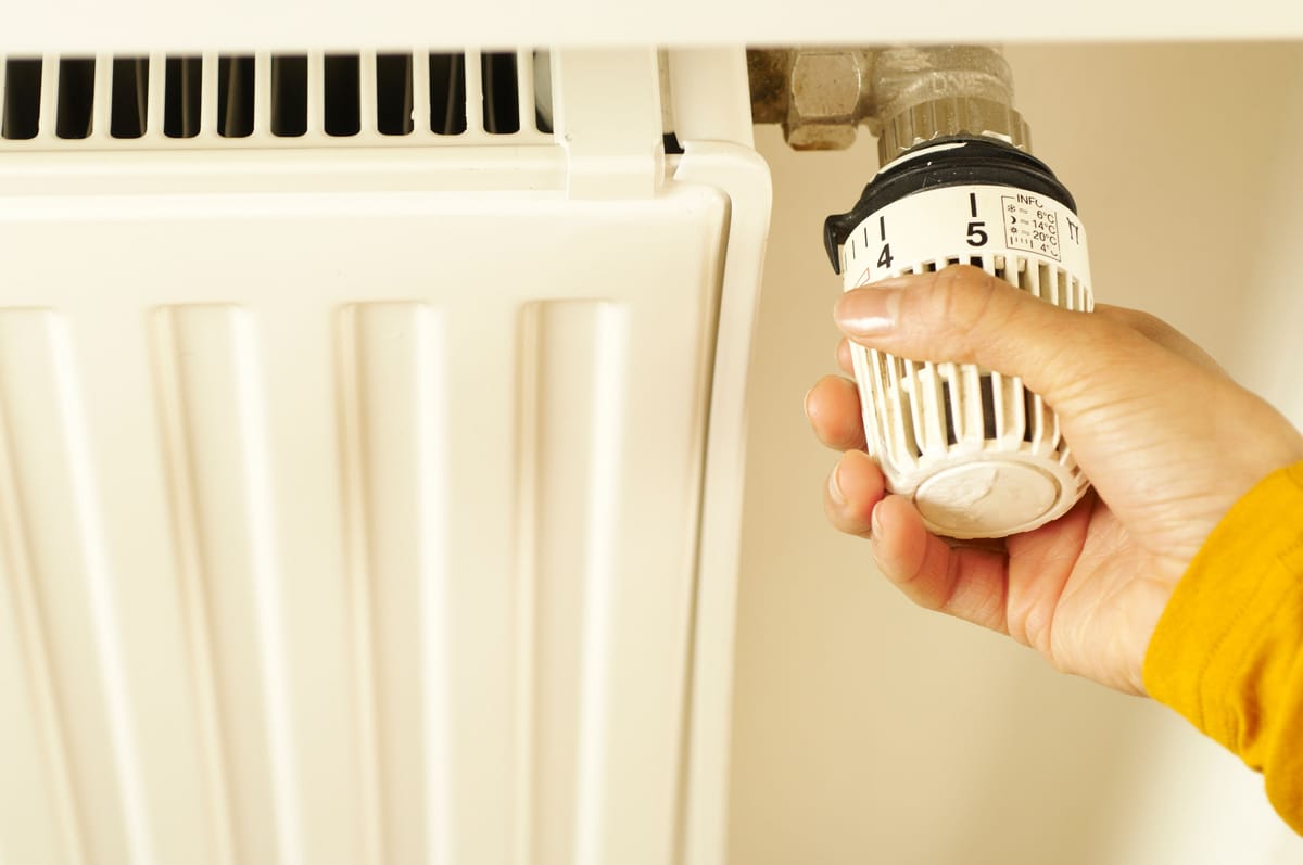 Hand turning the thermostatic knob of a radiator
