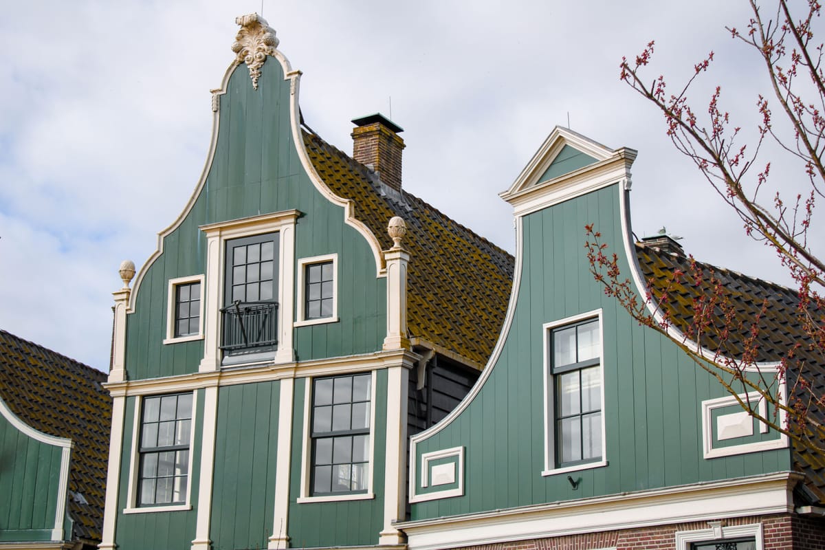 Groene houten Zaanse gevels met crèmewitte lijsten en kozijnen
