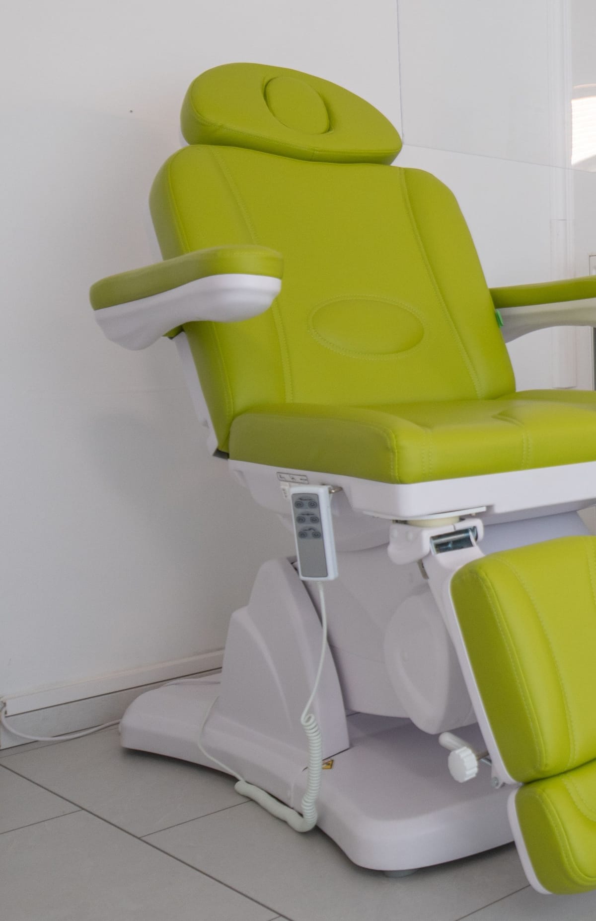 Un fauteuil de soin vert vide dans un cabinet de pédicure lumineux