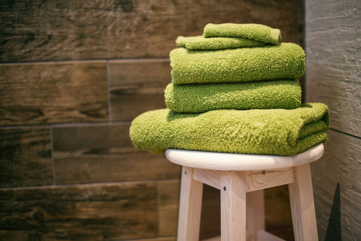 Gevouwen groene handdoeken op een houten krukje