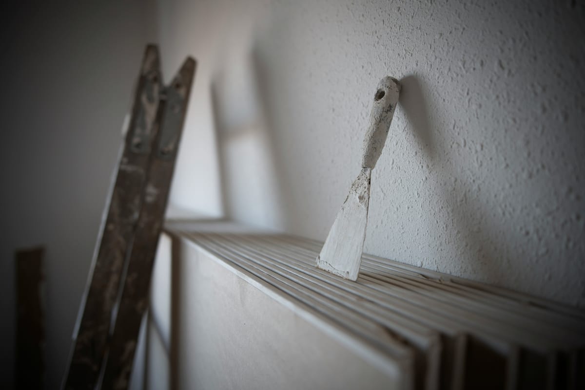 Plamuurmes tegen een gestucte muur naast een trap