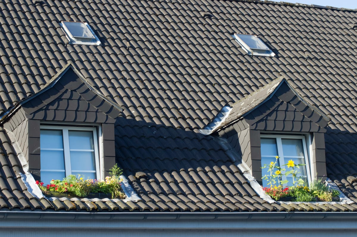 Grijs pannendak met twee dakkapellen en bloembakken