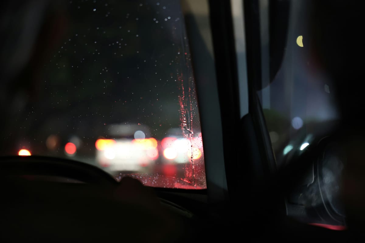 Regen op de voorruit, rode achterlichten in de avond